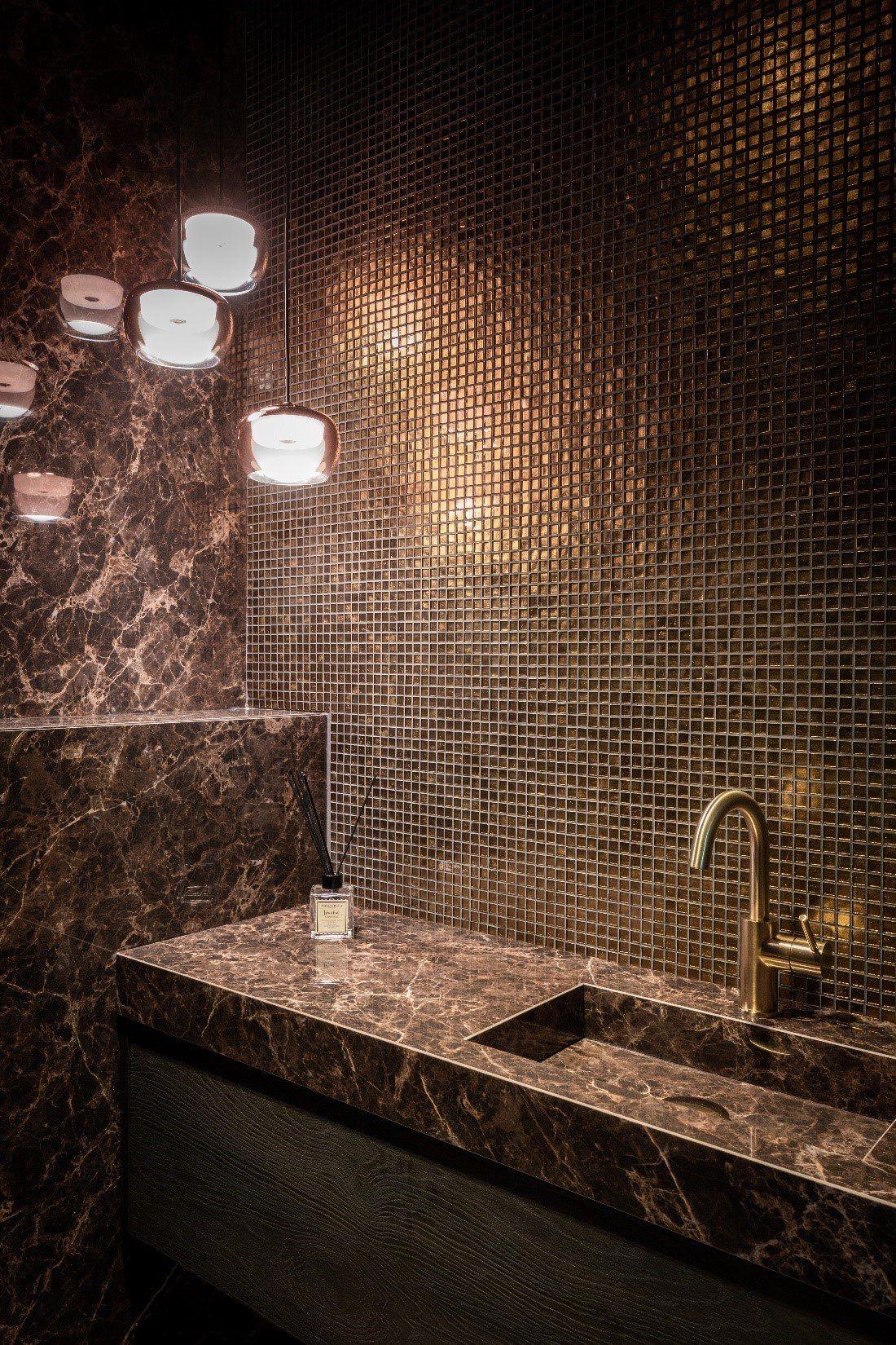Waschtisch aus braunem Marmor vor goldener Mosaikwand