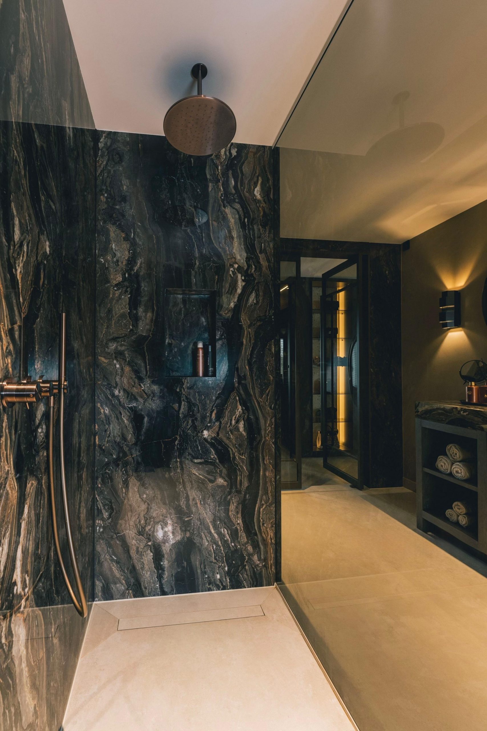 Dusche mit dunkler Natursteinwand und Regenbrause