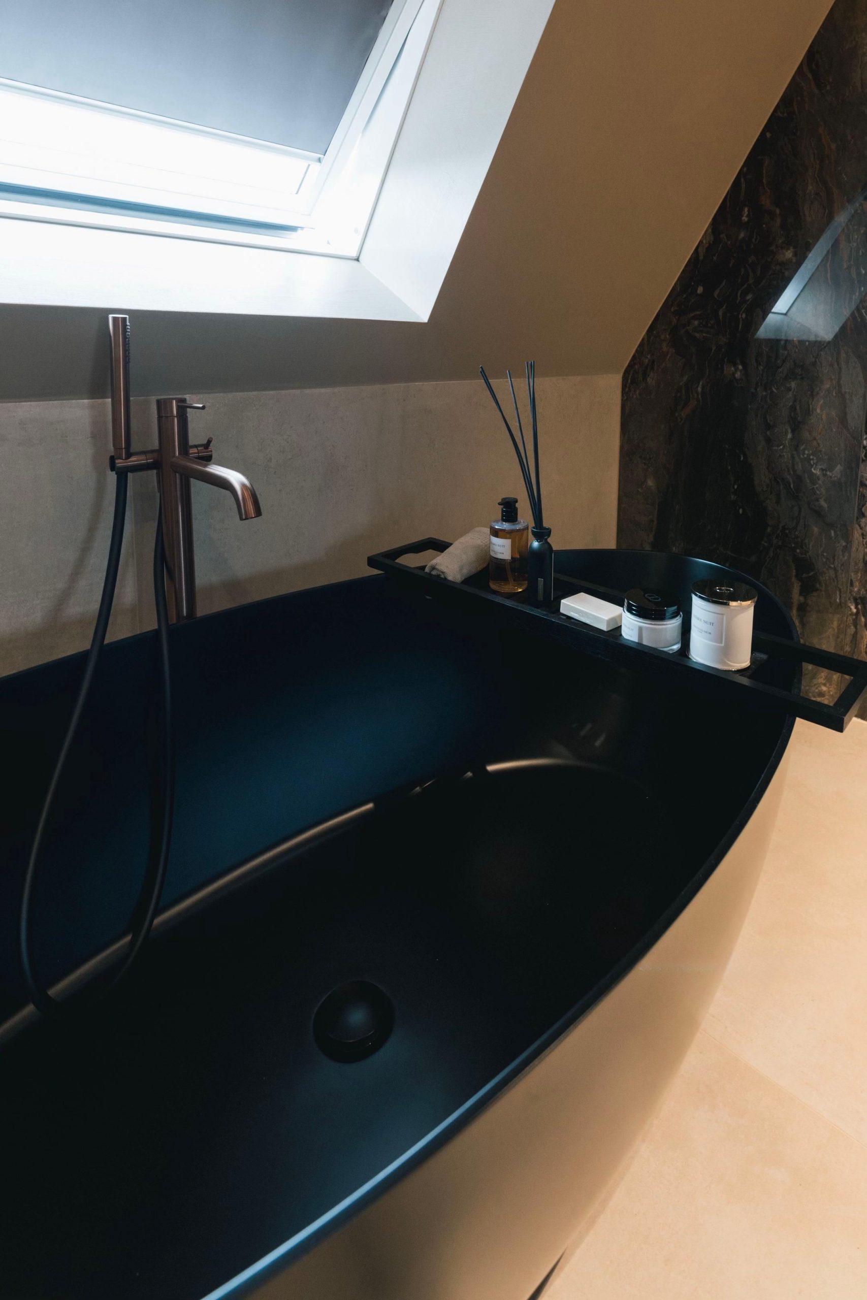 Schwarze freistehende Wanne unter einem Dachfenster