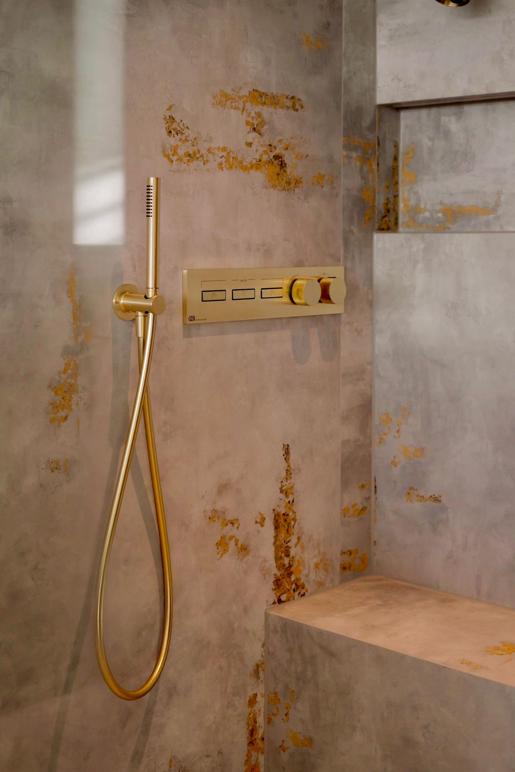 Duscharmatur in Gold auf fugenloser Kalkputzwand