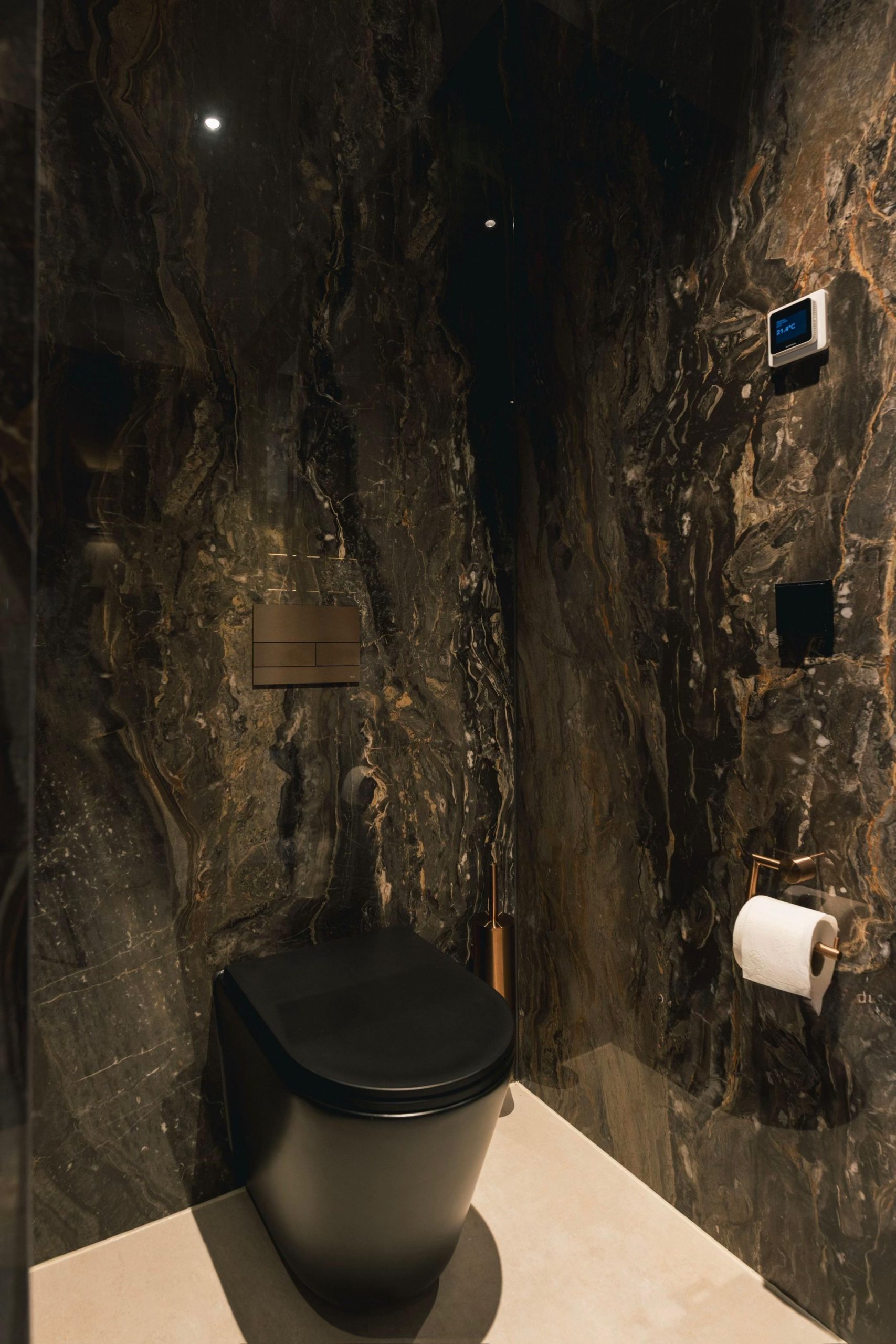 Gäste-WC mit schwarzer Marmorwand und Messingdetails